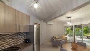 A modern kitchen with a built-in refrigerator, a dining area with a table and chairs, and a sofa. - Althea Suites 3 by Rentals Pro - Nea Moudania Halkidiki (Nea Moudania)