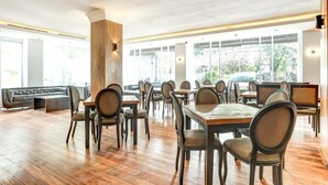 Een ruime restaurantruimte met houten vloeren, meerdere tafels en stoelen, en grote ramen met uitzicht op het omliggende landschap.