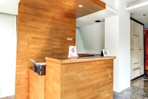 Una reception con finiture in legno, una insegna e un cestino nero.