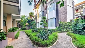 A modern building with a paved pathway, surrounded by lush greenery and palm trees. - Luxury Two Bedroom Villa with Pool and WiFi Access (Bali)