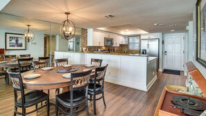 Een moderne keuken met witte kasten, een centraal eiland en een eetgedeelte met een houten tafel en stoelen.