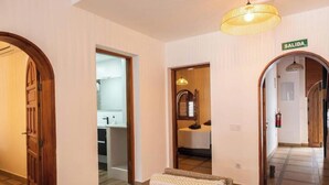 Un couloir d’hôtel avec des portes en bois, un lit, une salle de bain et un panneau indiquant « SORTIE ».