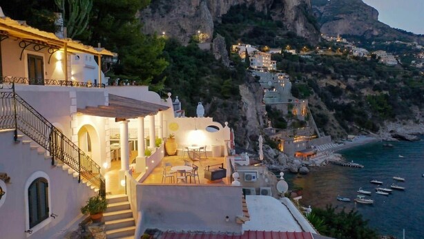 Un edificio costiero con una scala, posti a sedere all'aperto e vista sul mare e sulle scogliere.