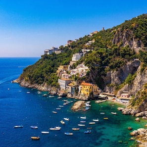 A coastal town with buildings on a hillside, boats in the water, and a clear view of the sea.
