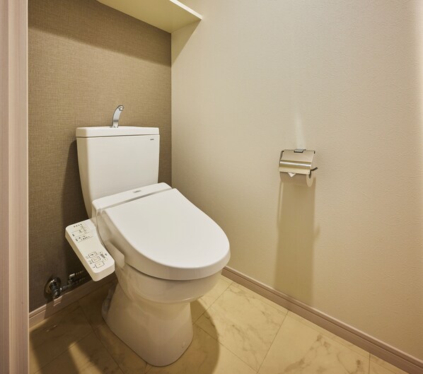 Des toilettes modernes dotées d’un panneau de commande, d’un porte-rouleau de papier toilette fixé au mur et d’un mur à texture.