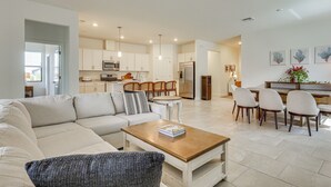 A modern living room with a sofa, coffee table, and dining area with chairs. - New Home in Verdana Village w/ Resort Amenities! (Estero)