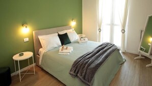 A neatly made bed with pillows and a blanket, a bedside table with a bowl, a small stool, and a mirror on the wall. - Federica Flat - Metro Monte Grappa (Turin)