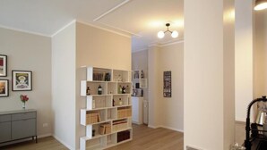 A modern interior with a white bookshelf, a grey console, and a radiator. - Federica Flat - Metro Monte Grappa (Turin)
