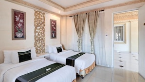 Habitación de hotel con dos camas, un panel decorativo en la pared, una planta en maceta y vista al pasillo.