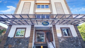Entrada de hotel con un vestíbulo cubierto, un letrero y fachada de piedra.