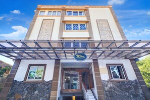 A hotel entrance with a covered walkway, a sign, and a stone facade. - Cozy Solo Stay with Free WiFi Parking and Pool (Bali)