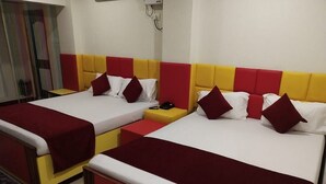 Ein Hotelzimmer mit zwei Betten, jeweils mit einem roten und gelben Kopfteil, weißer Bettwäsche und roten Kissen.