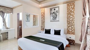 Een hotelkamer met een bed, een bureau, een douche en decoratieve muurkunst.