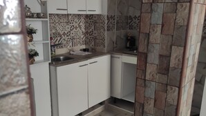 Cocina con armarios blancos, salpicadero estampado y suelo de mármol.