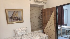 Una habitación con una cama, un cuadro, un baño con ducha y una puerta con diseño geométrico.
