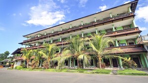 Un edificio a più piani con balconi, circondato da palme.