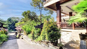 Un edificio tradizionale con un balcone, immerso nel verde e sotto un cielo sereno.