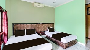 Camera d'albergo con due letti, una testiera, un condizionatore d'aria e una tenda rossa.