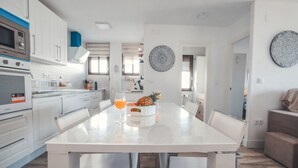 A modern kitchen with white cabinets, a large island, and a dining area with chairs. - Baylight Retreat Apartment (El Puerto de Santa María)