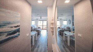A modern interior with a dining area, sofas, and a view through a glass door. - Baylight Retreat Apartment (El Puerto de Santa María)