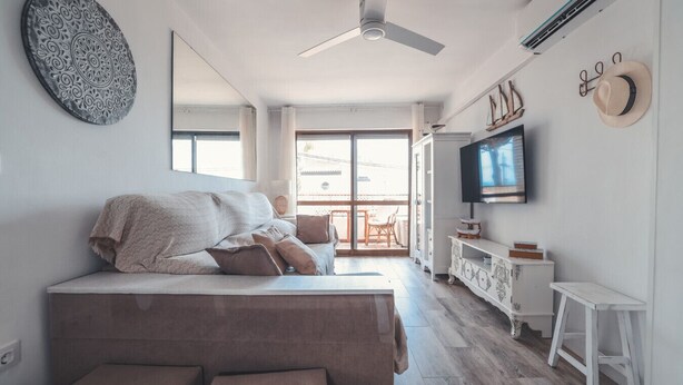 A modern bedroom with a large bed, a ceiling fan, a TV, and a view to the outside. - Baylight Retreat Apartment (El Puerto de Santa María)