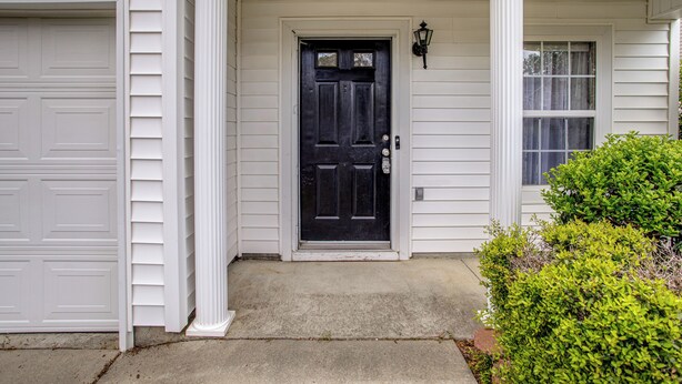 A house with a black front door, white columns, a garage door, and a window with curtains. - Great for Military Families! Quiet Columbia Home (Columbia)
