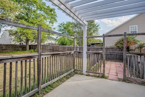A covered patio area with a wooden fence, a concrete pathway, and a house in the background. - Great for Military Families! Quiet Columbia Home (Columbia)