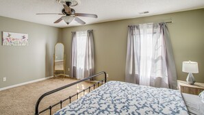 A bedroom with a bed, ceiling fan, window with curtains, and a bedside table with a lamp. - Great for Military Families! Quiet Columbia Home (Columbia)