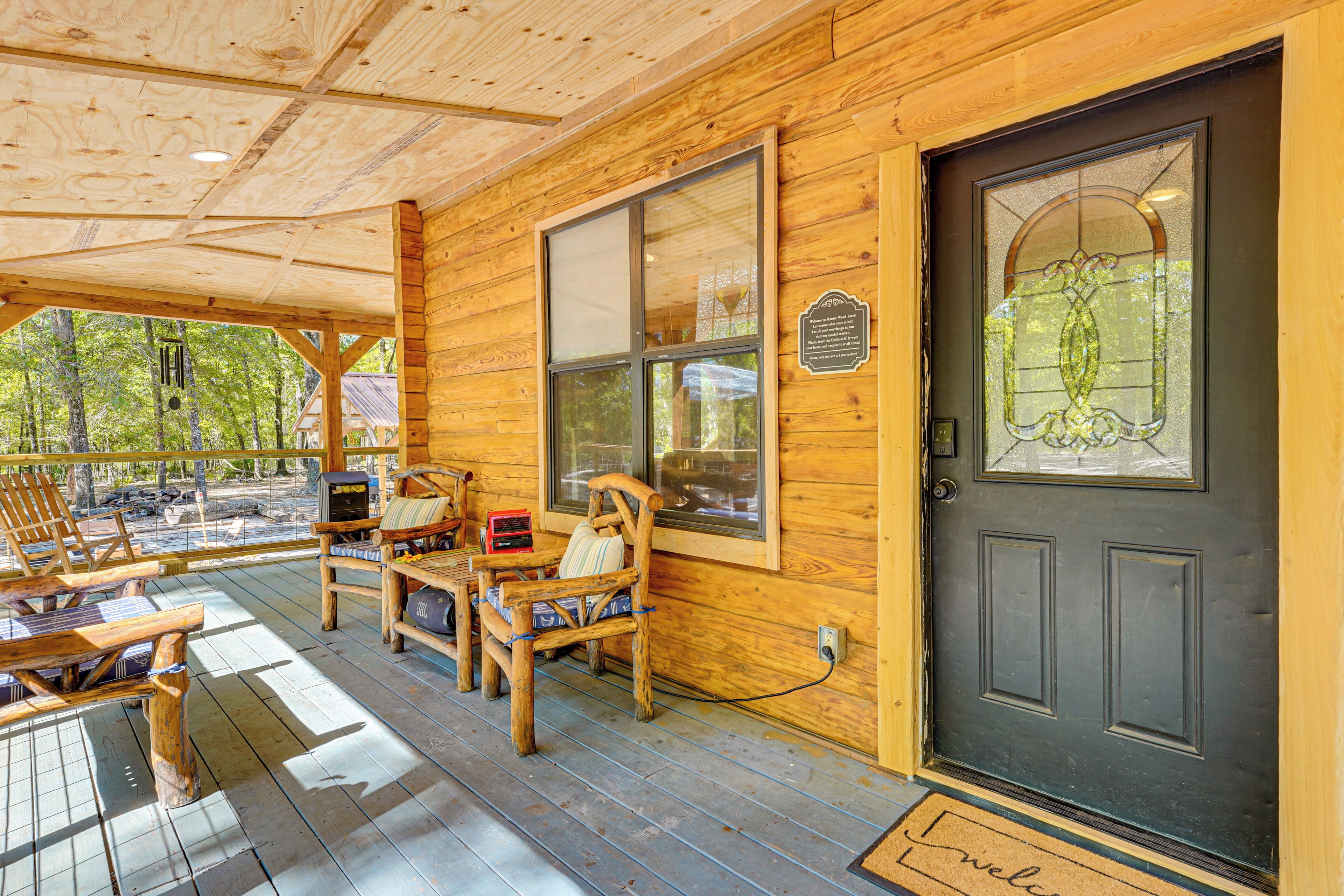 A wooden cabin with a porch, a black door, and a bench.