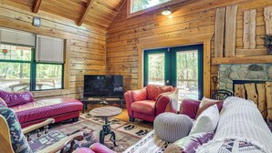 A log cabin interior with a fireplace, leather sofas, a television, and a stone wall. - Fish & Float at Natural Springs! Log Cabin in Bell (Bell)