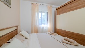 A bedroom with a bed, pillows, a window with curtains, and a wooden wardrobe. - Villa Danijela by Villas Guide (Barban)