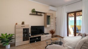 A modern living room with a flat-screen TV, wooden cabinets, a glass coffee table, and a view of a pool through a sliding glass door. - Villa Danijela by Villas Guide (Barban)