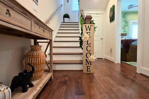 Eine Holztreppe mit einem 'WELCOME'-Schild, einer Vase und einer kleinen Katzenfigur.