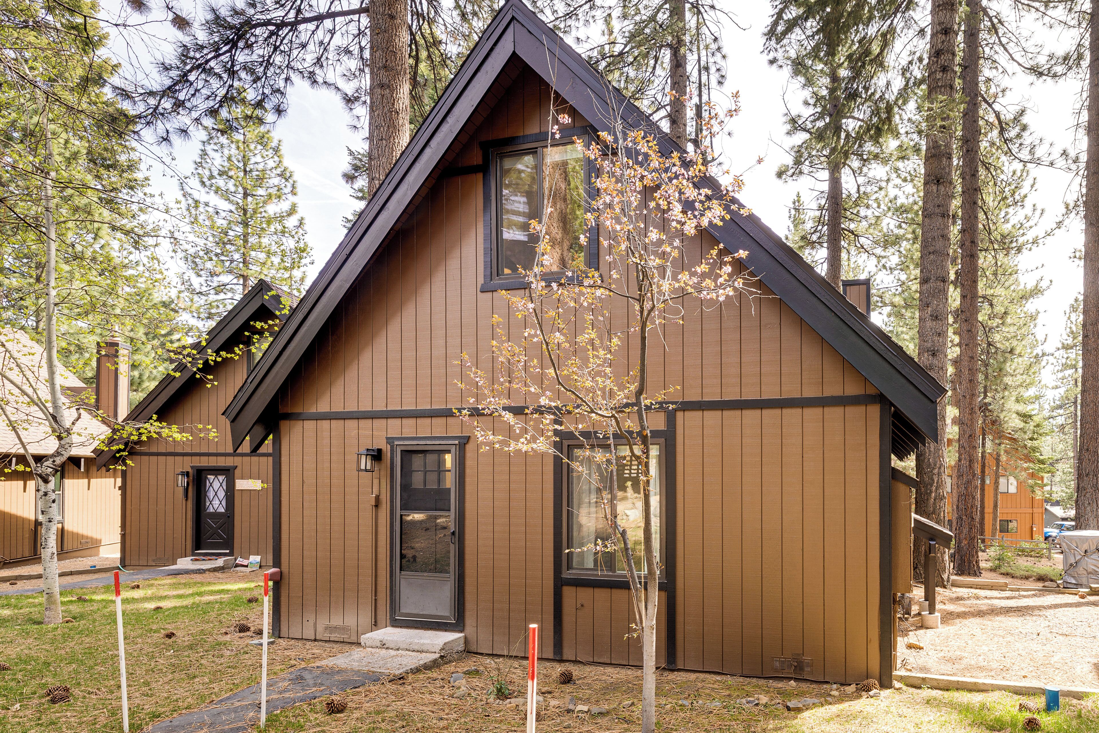 Une cabane à l’extérieur brun foncé, avec une porte d’entrée et une fenêtre.