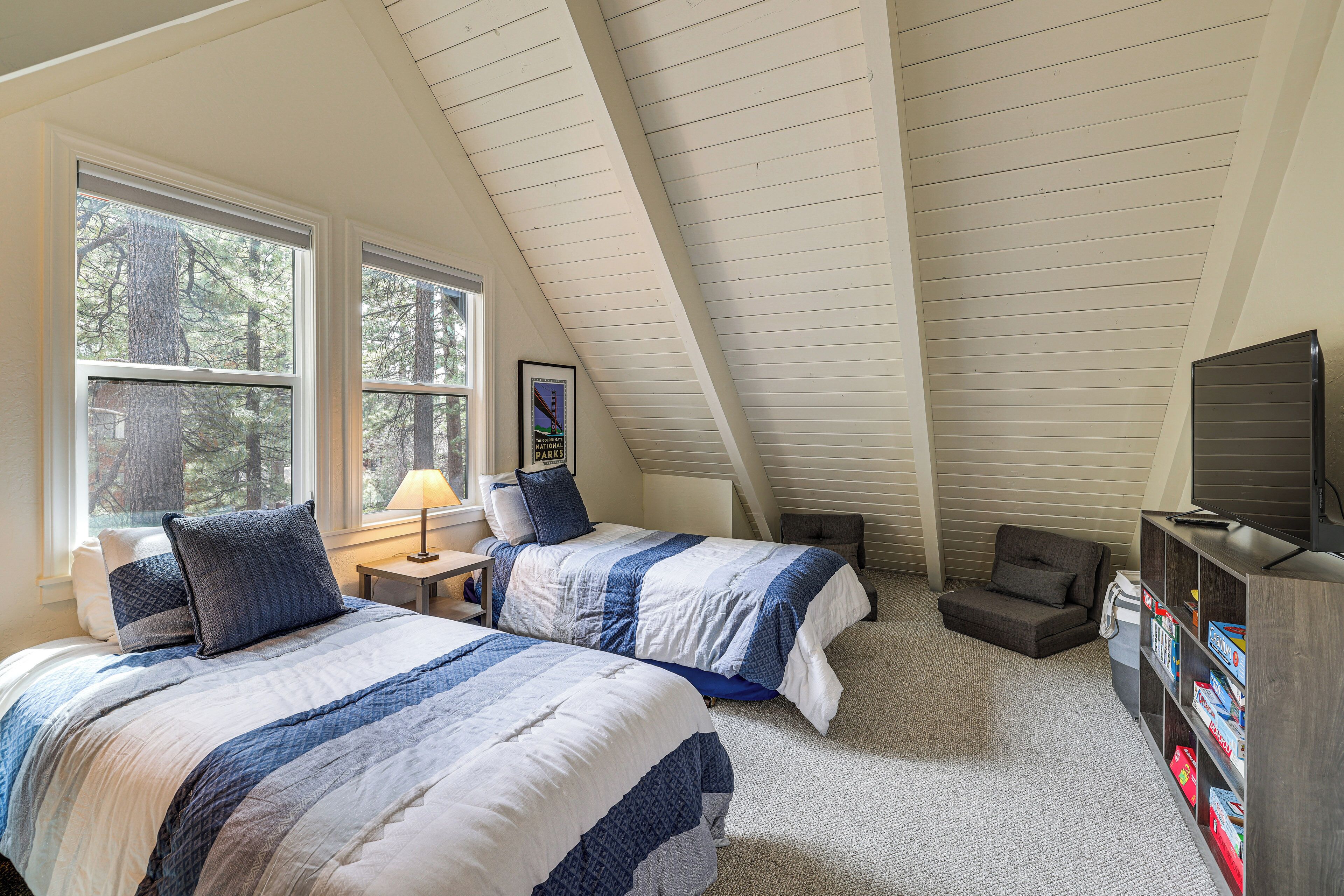 A bedroom with two beds, a sofa, a TV, and a bookshelf.