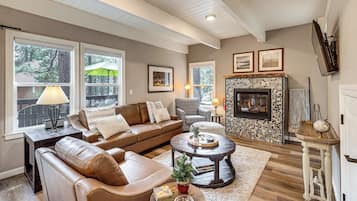 A living room with a fireplace, leather sofa, coffee table, and a stone fireplace surround.