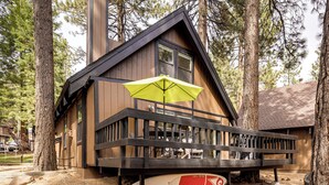 Eine Holzhütte mit Balkon, einem Surfbrett und einem gelben Sonnenschirm.