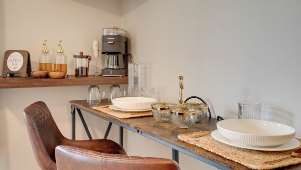 Ett matbord med en kaffebryggare, glasburkar och en skylt som visar att det finns en kaffebar här.