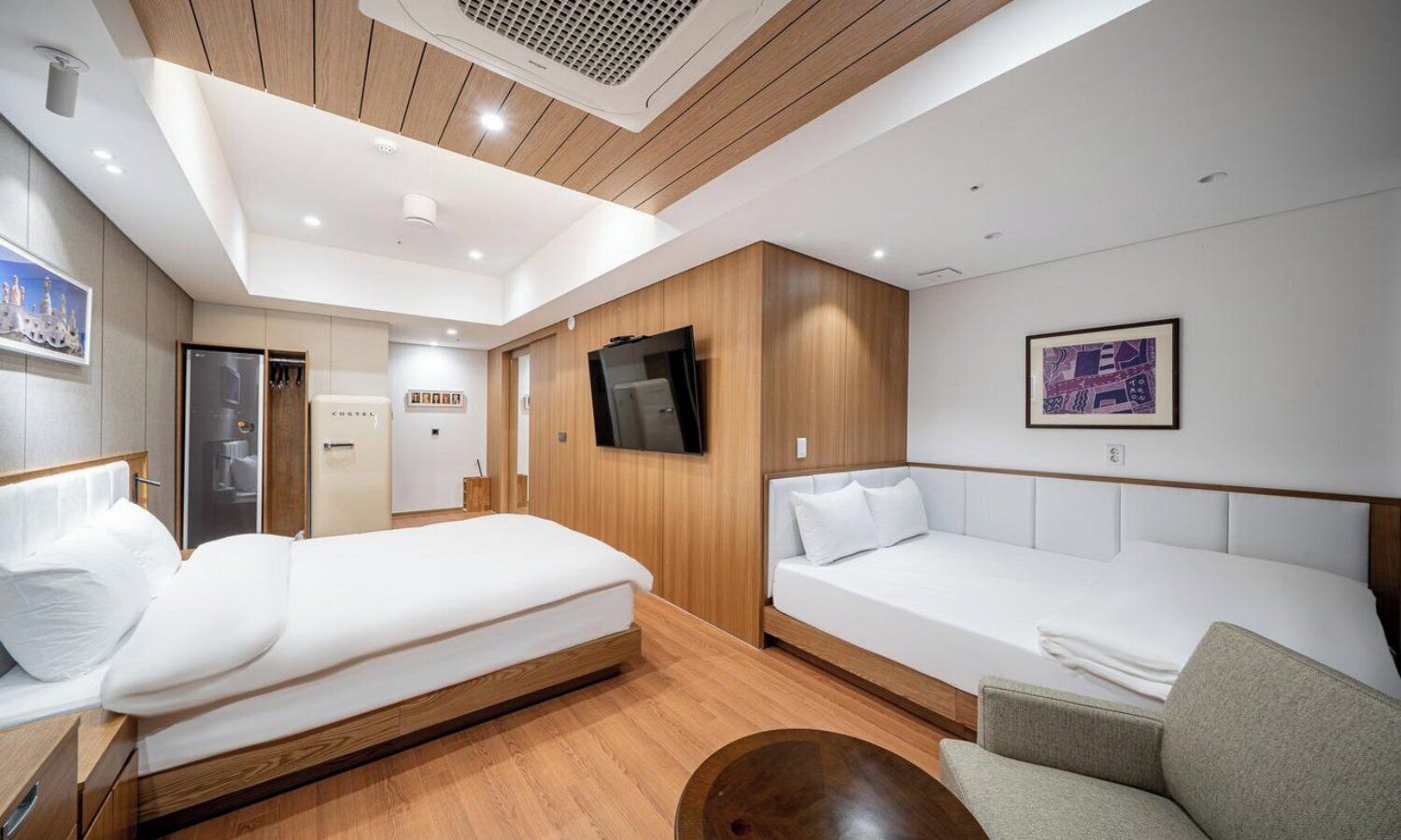 Une chambre d’hôtel moderne équipée d’un lit, d’un canapé, d’une télévision et d’une petite table.