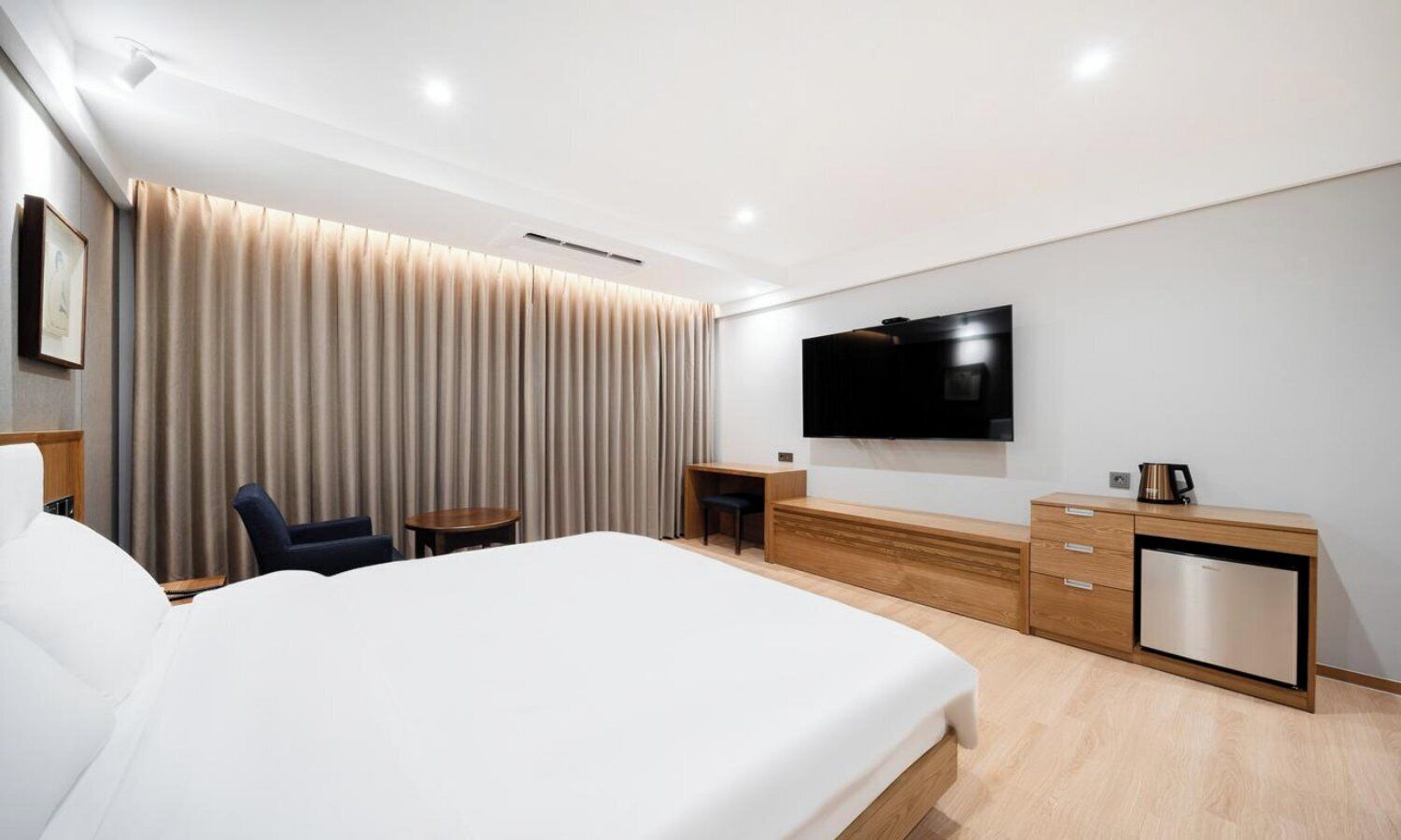 Una habitación de hotel moderna con una cama grande, un televisor, un escritorio y una cafetera.