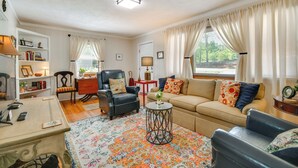 A living room with a sofa, armchairs, a coffee table, a TV, and a bookshelf. - Near Horse Shows & Events! Blissful Tryon Cottage (Tryon)
