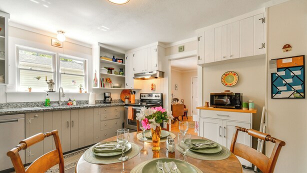 A modern kitchen with white cabinets, a dining table set for four, and a microwave on the countertop. - Near Horse Shows & Events! Blissful Tryon Cottage (Tryon)