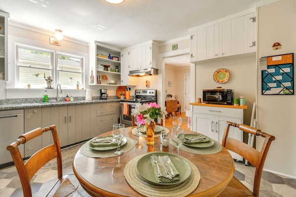 A modern kitchen with white cabinets, a dining table set for four, and a microwave on the countertop.