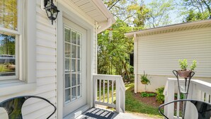 A porch with two chairs, a door with a window, and a small shed with plants. - Near Horse Shows & Events! Blissful Tryon Cottage (Tryon)