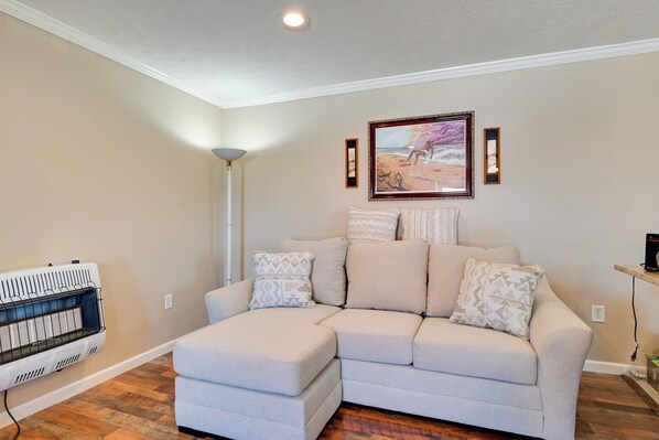 A living room with a sectional sofa, a standing lamp, a framed painting, and a built-in heater.