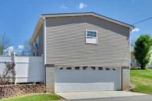A single-story house with a garage, a small window on the upper floor, and a white fence.