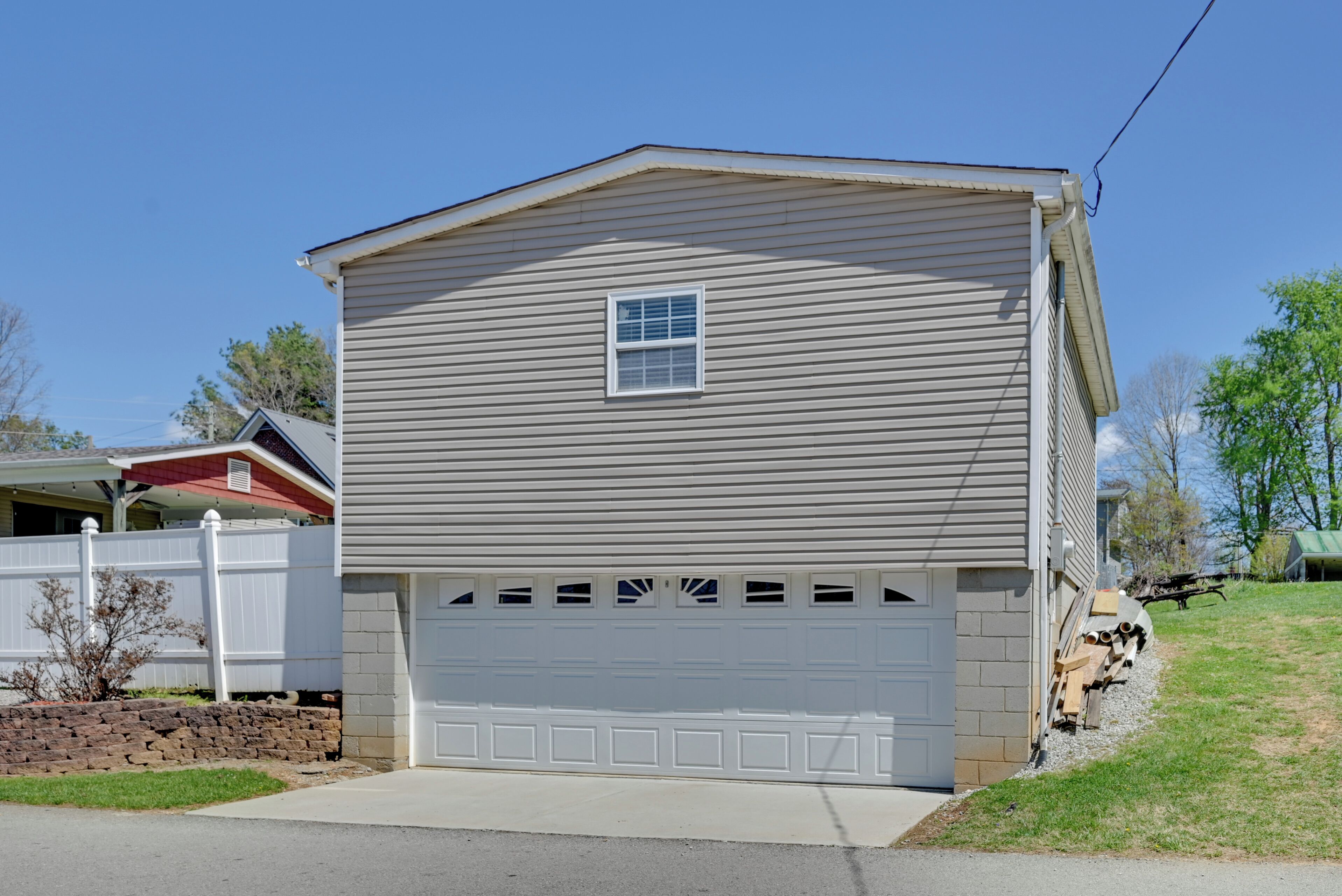 Une maison de plain-pied avec un garage, une petite fenêtre et une clôture blanche.