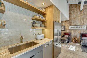 Eine moderne Küche mit Edelstahlspüle, Geschirrspüler und integriertem Kühlschrank.