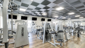 Una palestra con diverse macchine per esercizi, tra cui panche pesi e attrezzature cardio.