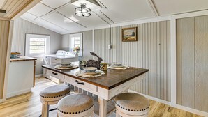 A kitchen with a wooden island, bar stools, a dining table, and a hanging light fixture. - Surrounding Pasture Views! Peaceful Escape in Iuka (Iuka)